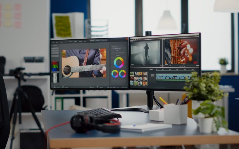 Empty creative workplace with professional computer placed on desk, dual monitor setup. Video editing start up studio company agency with no people in it and post production software on pc displays